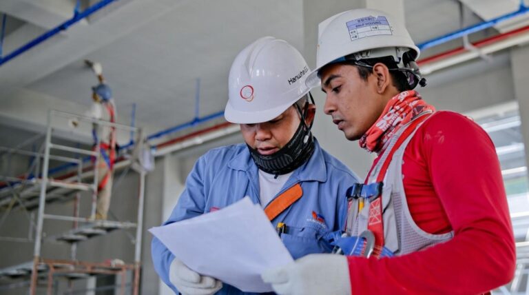 Construction workers reviewing blueprints on site.